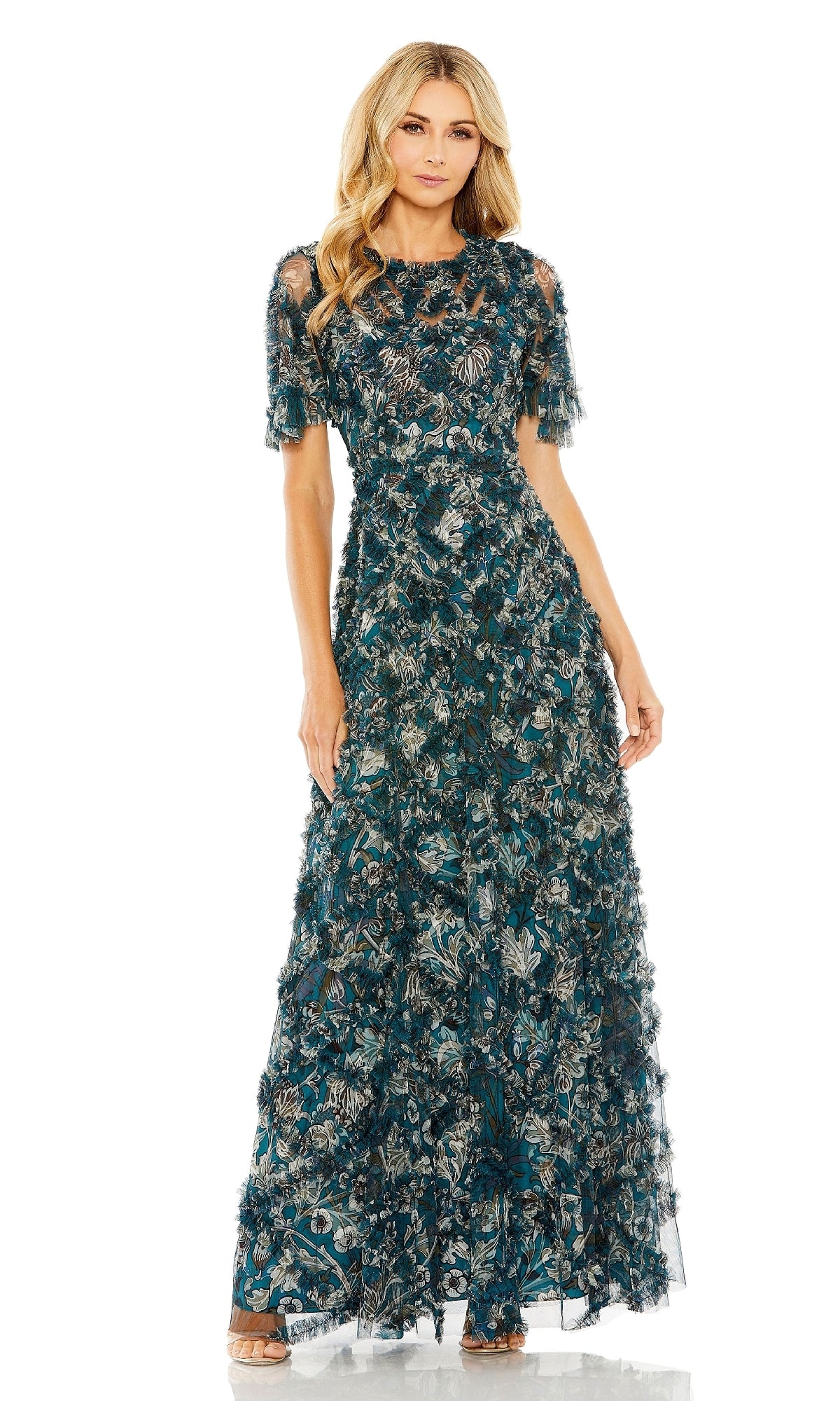 Woman poses against a white background in the Mac Duggal 8043 long formal dress, a floor-length, short-sleeved gown in dark teal floral fabric with textured and feather details.